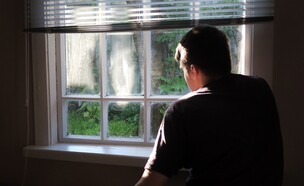 איש מודאג מסתכל מהחלון (צילום: Sabphoto, shutterstock)