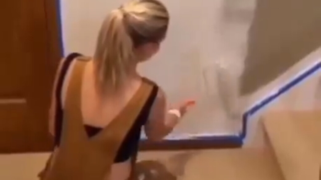 בחורה מנסה לצבוע כתם צל בקיר בחורה מנסה לצבוע כתם צל בקיר