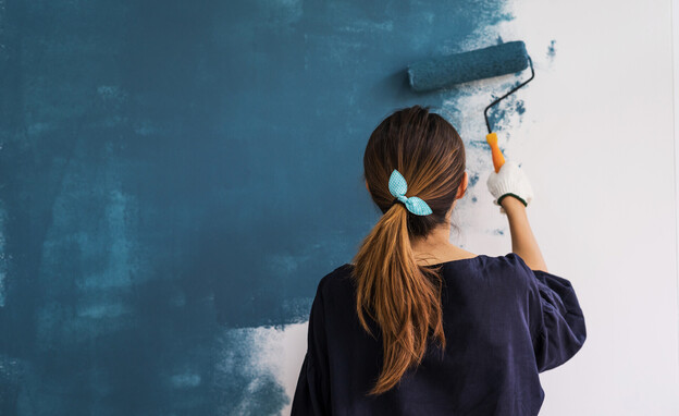 בחורה צובעת קיר בכחול, מבט מאחור (צילום: kitzcorner, SHUTTERSTOCK)