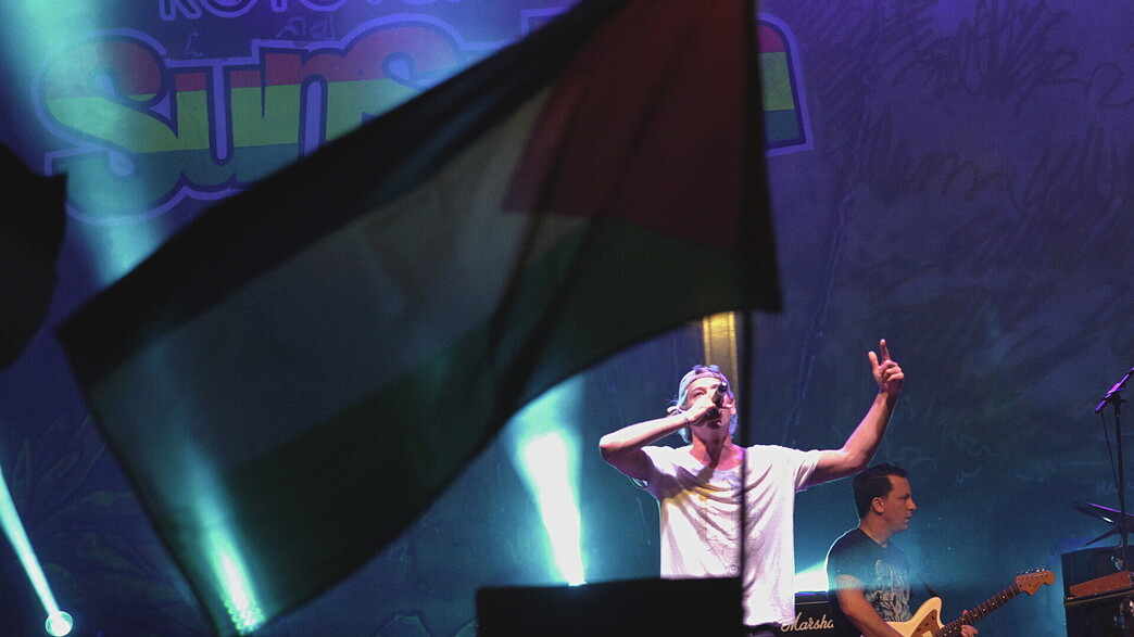 דגל פלסטיני מתנוסס בזמן שהמוזיקאי היהודי-אמריקני מתיסיהו דגל פלסטיני מתנוסס בזמן שהמוזיקאי היהודי-אמריקני מתיסיהו