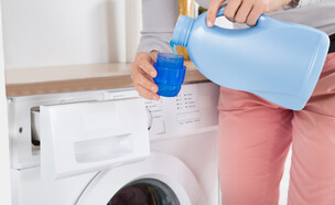 אישה שופכת נוזל כביסה מבקבוק לפקק, מכונת כביסה (צילום: Andrey_Popov, SHUTTERSTOCK)