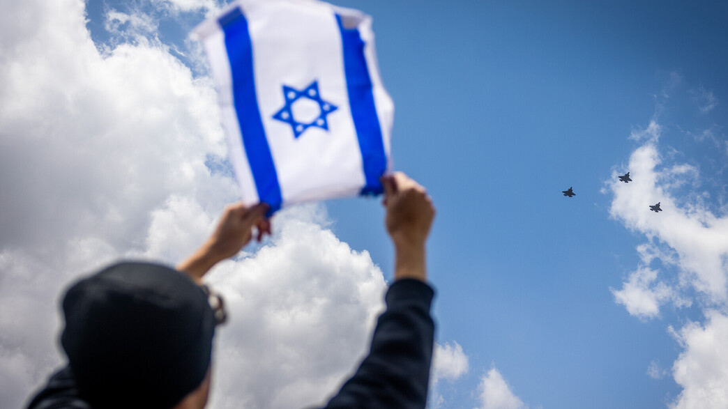 אדם מניף דגל מול מטס יום העצמאות