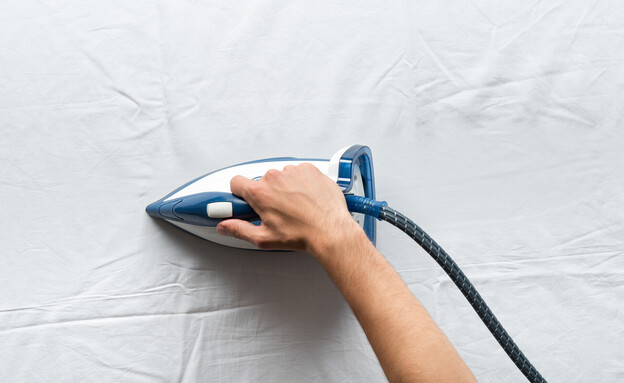 גיהוץ, יד עם מגהץ על בד לבן (צילום: LightField Studios, SHUTTERSTOCK)