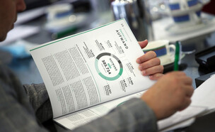 עיתונאי קורא את הדוח הפיננסי של חברת DFB (צילום: Alex Grimm, Getty Images)