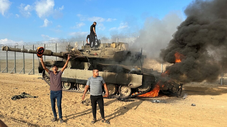 פלסטינים חוגגים סביב טנק צה"ל שהותקף ב-7 באוקטובר (צילום: רויטרס)
