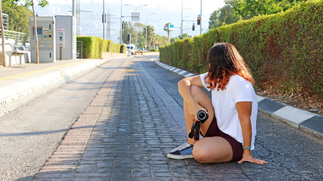 נערה עם מצלמה מחכה לאוטבוס בחיפה (אילוסטרציה: Ricky goshen, shutterstock)