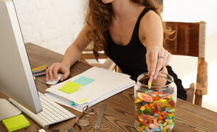 אישה אוכלת ממתקים במשרד (צילום: By Dafna A.meron, shutterstock)