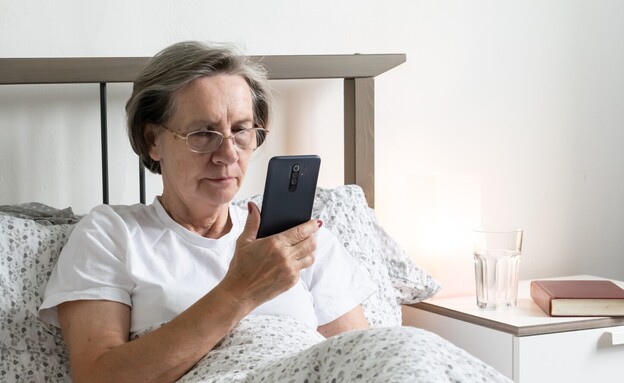 אישה מבוגרת מחזיקה סמארטפון, אילוסטרציה (צילום: metodej, Shutterstock)