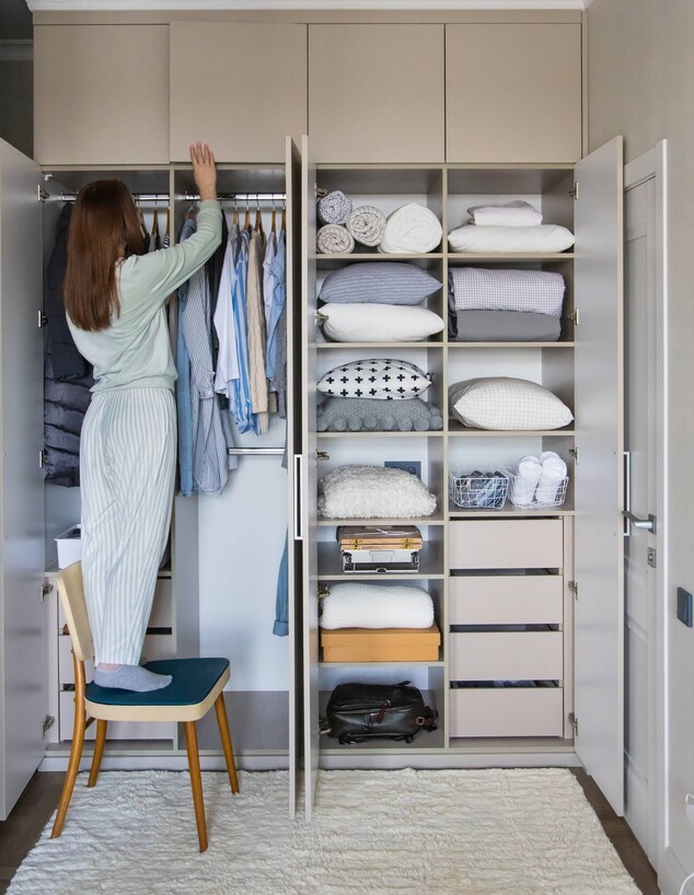 אישה מסדרת ארון בגדים