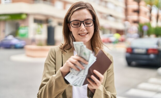 אישה סופרת דולרים ברחוב (אילוסטרציה: Krakenimages.com, shutterstock)