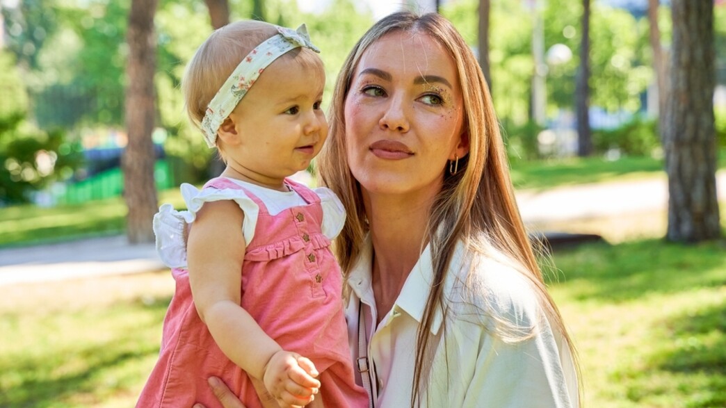 אמא מחזיקה בתינוקת בפארק