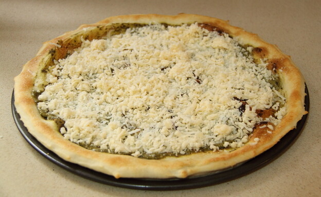 עכשיו שהבצק חצי אפוי, יותר קל לתפעל את הפיצה