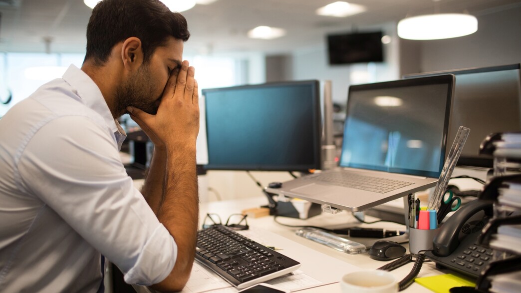 עובד מודאג עם ראש בין הידיים עובד מודאג עם ראש בין הידיים