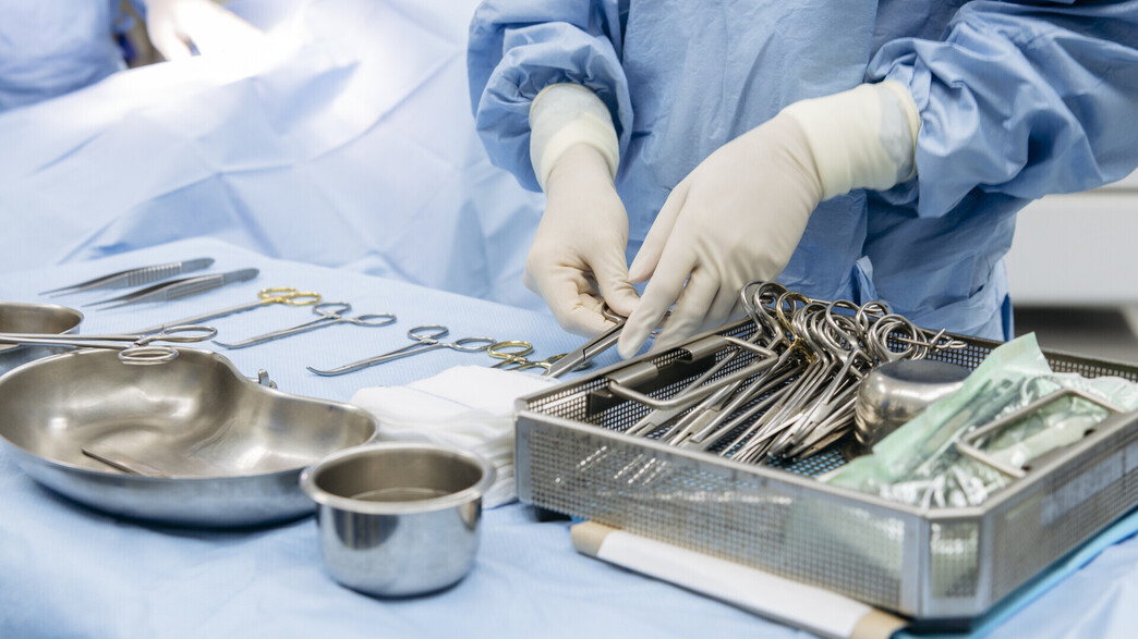 מנתח מניח כלים על מגש בחדר ניתוח