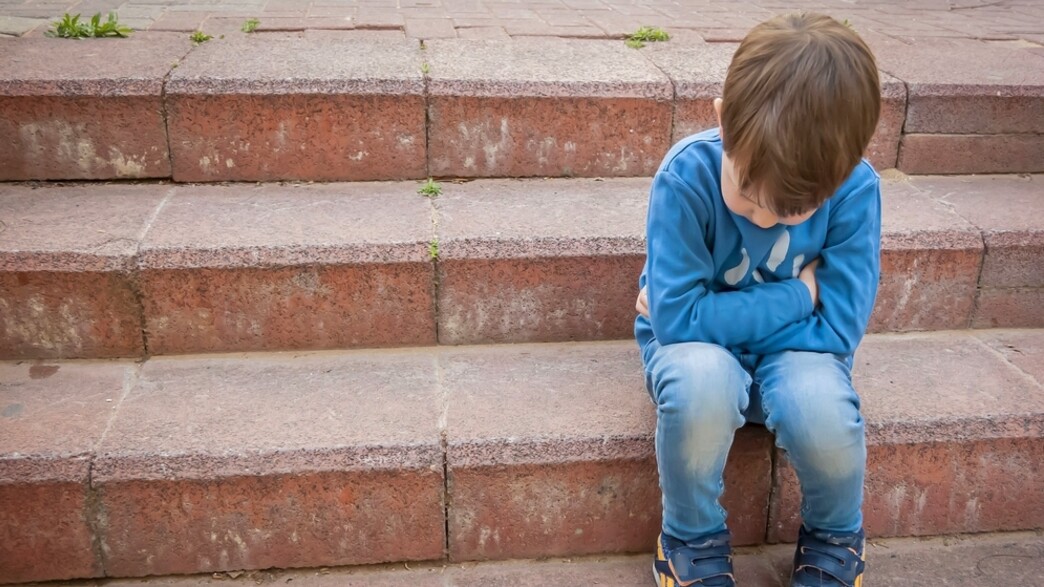 ילד עצוב יושב על מדרגות