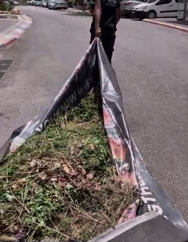 פועלים מטעם עיריית חיפה מפנים גזם בעזרת שלט החזרת (צילום: לפי סעיף 27 א')