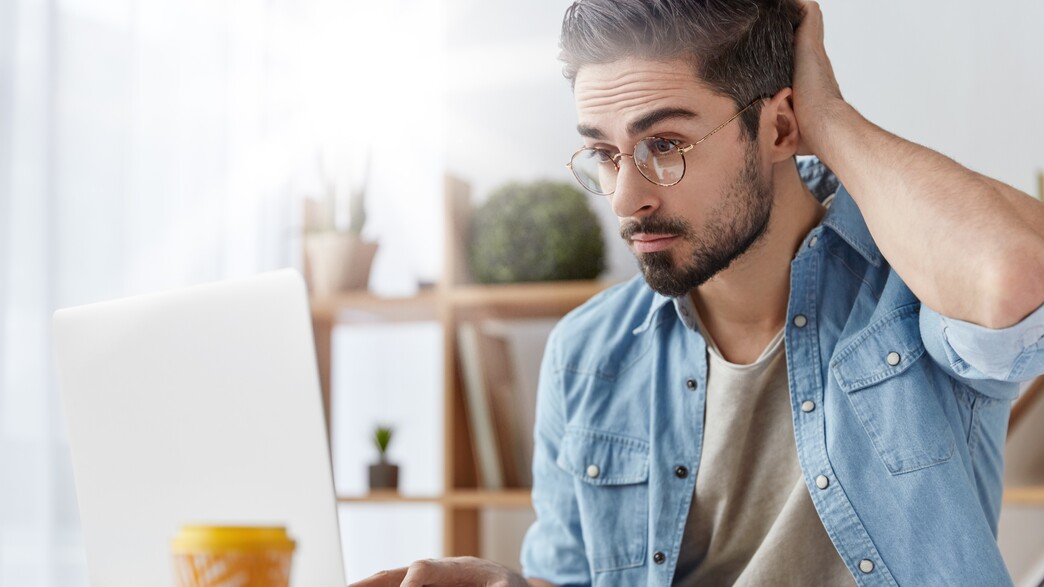 גבר עובד על מחשב נייד, חושב, מגרד בראש