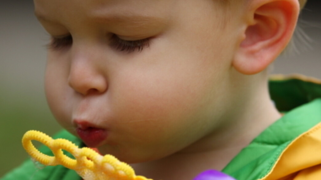 פעוט נושף על צעצוע של בועות סבון פעוט נושף על צעצוע של בועות סבון