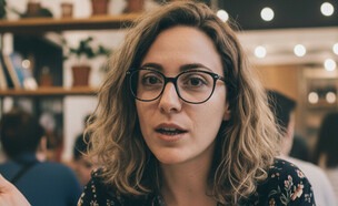 אישה צעירה יושבת בבית קפה (AI: mako)