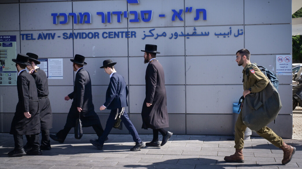 חרדים בדרך להפגנה בירושלים, לצד חייל ברכבת