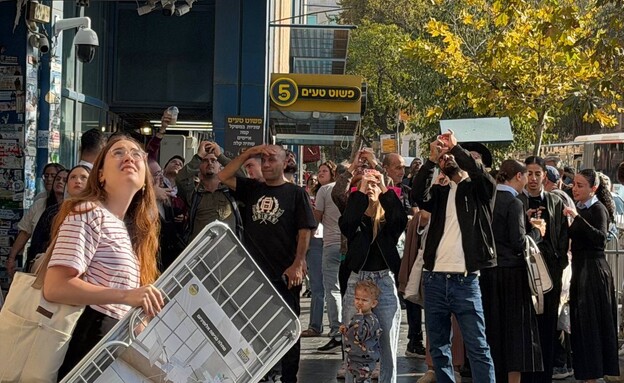 עוברי אורח מסתכלים על הנער שנלכד על העגורן 