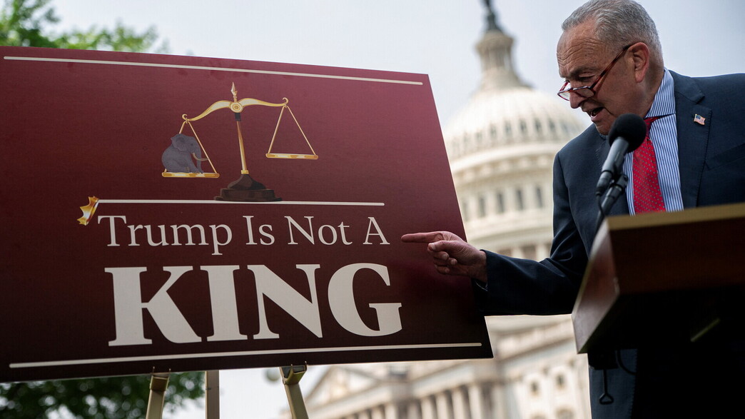 מנהיג המיעוט בסנאט שומר לצד כרזה נגד טראמפ