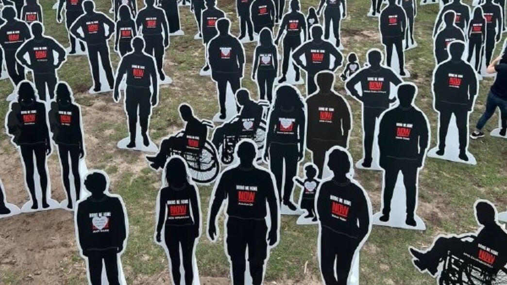 שלטי חטופים על רקע החוף שבו בוצע הטבח: המיצג בזמן המאבק - והמשפחות שסיפרו על אנטישמיות כבר אז