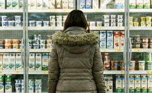 אישה עומדת מול מקרר מוצרי חלב בסופרמרקט (AI: mako)