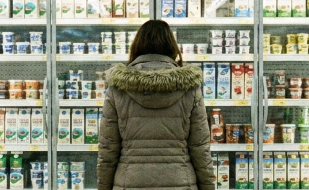 אישה עומדת מול מקרר מוצרי חלב בסופרמרקט