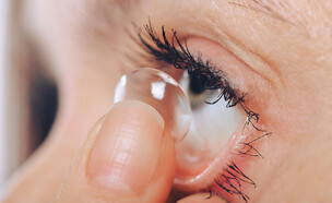 אישה מרכיבה עדשות מגע (צילום: Dmytro Khlystun, Shutterstock)