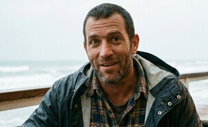 גבר יושב בבית קפה ליד הים (AI: mako)