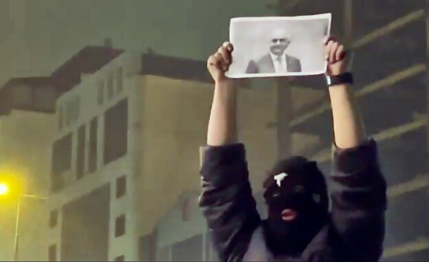 מפגין איראני מחזיק בתמונה של רזא פהלווי בהפגנות