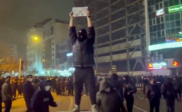 מפגין איראני מחזיק בתמונה של רזא פהלווי בהפגנות