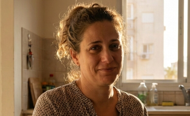 אישה יושבת במטבח ביתה ומסתכלת למצלמה (AI: mako)