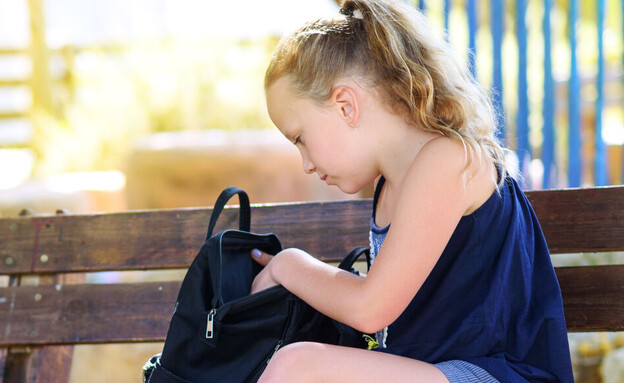 ילדה מחטטת בתיק בית הספר שלה
