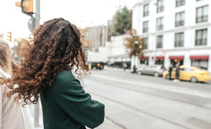 אישה עם שיער מתולתל ממתינה לאוטובוס (צילום: 123RF‏)