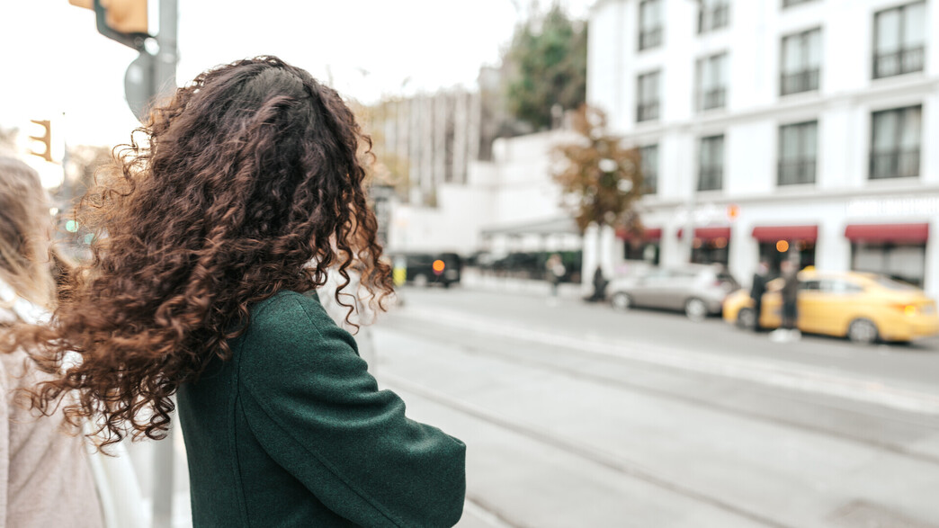 אישה עם שיער מתולתל ממתינה לאוטובוס