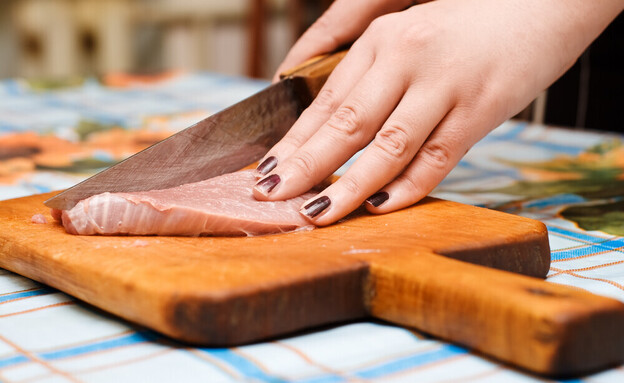 חותכת בשר על קרש חיתוך (צילום: Shutterstock)