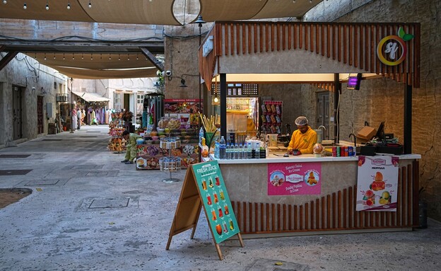 מוכר משקאות קלים ממתין ללקוחות בשוק אל סיף הריק בדובאי