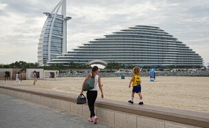 אישה וילדה צועדים לאורך חוף הים בדובאי, כשברקע מלונות  (צילום: ap)