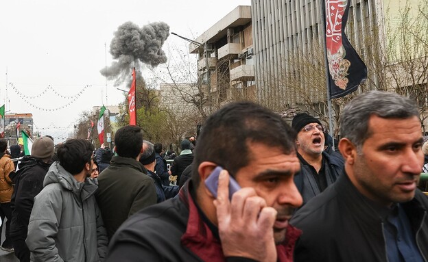עשן מפיצוץ מאחורי מפגינים במהלך צעדת "יום אל-קודס"