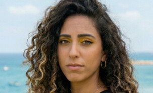 אישה עומדת בפארק ליד הים (AI: mako)