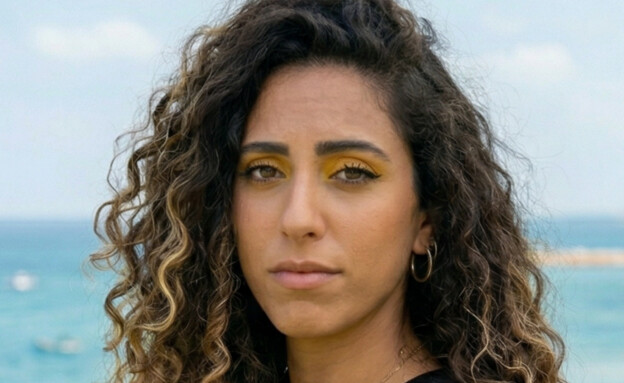 אישה עומדת בפארק ליד הים (AI: mako)