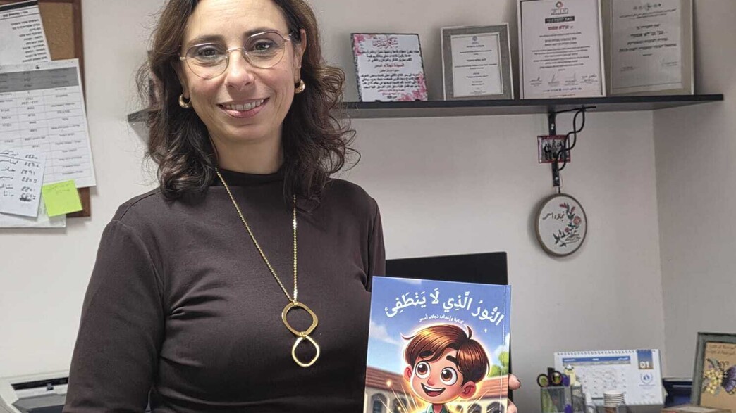 נג'לאא אסמר עם הספר "האור שלא נכבה"