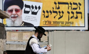 חרדי לצד שלט של ש"ס עם הרב עובדיה יוסף (צילום: דוד כהן, פלאש 90)