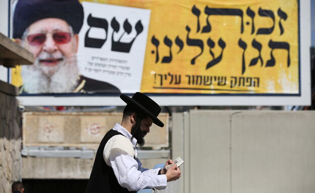 חרדי לצד שלט של ש"ס עם הרב עובדיה יוסף (צילום: דוד כהן, פלאש 90)