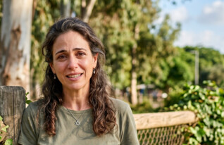 אישה עומדת בפארק (AI: mako)