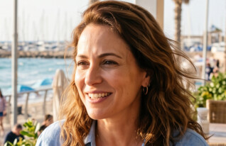 אישה יושבת בבית קפה ליד הים (AI: mako)