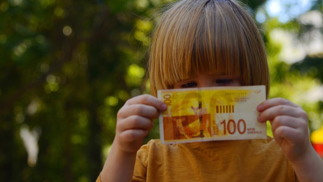 ילד מחזיק שטר של 100 שקל ילד מחזיק שטר של 100 שקל