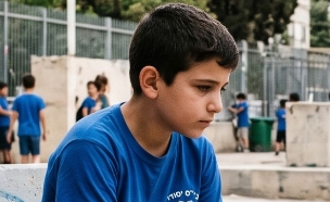 ילד יושב לבד בחצר בית הספר (AI: mako)